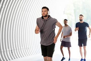 Image showing male friends with headphones running outdoors