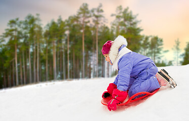 Image showing girl sliding down on snow saucer sled in winter