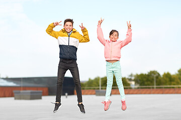 Image showing happy children jumping on roof and showing peace