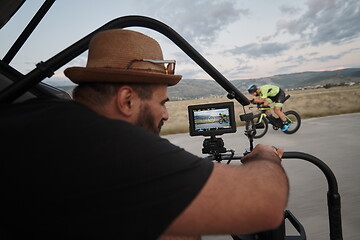 Image showing videographer taking action shot of triathlon athlete while riding bike