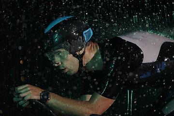 Image showing triathlon athlete riding bike fast on rainy night