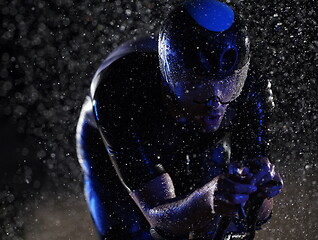 Image showing triathlon athlete riding bike fast on rainy night