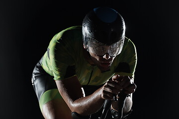 Image showing triathlon athlete riding bike fast at night