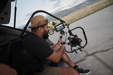 Image showing videographer taking action shot of triathlon athlete while riding bike