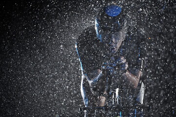 Image showing triathlon athlete riding bike fast on rainy night