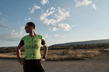 Image showing triathlon athlete resting and setting smartwatch