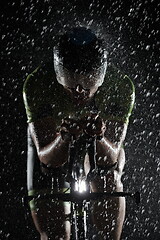 Image showing triathlon athlete riding bike fast on rainy night