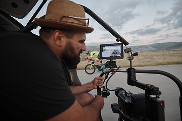 Image showing videographer taking action shot of triathlon athlete while riding bike