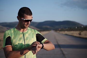 Image showing triathlon athlete resting and setting smartwatch