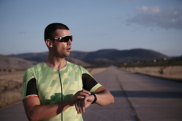 Image showing triathlon athlete resting and setting smartwatch