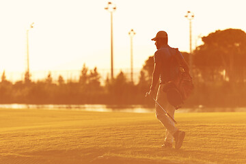 Image showing golfer  walking and carrying golf  bag at beautiful sunset