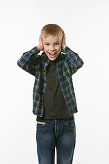 Image showing The boy covers his ears with his hands and shouts looking into the frame against a white background