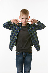 Image showing boy on a white background in a plaid shirt blows his cheeks with his fingers