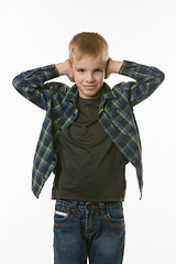 Image showing Boy covers his ears with his hands on a white background in everyday clothes