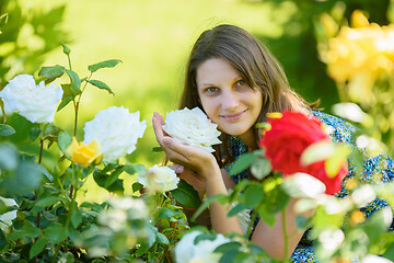 Image showing portrait of a smiling girl against the backdrop of roses in the park