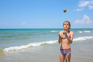 Image showing A girl of ten years juggles sand balls on the seashore