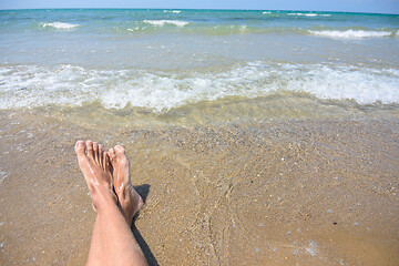 Image showing Feet of a man on a sandy beach, in the background a sea surf and horizon