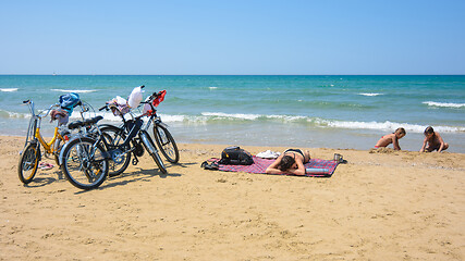 Image showing On the sandy seashore, a family arriving on bicycles rests