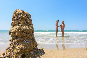 Image showing In the foreground a tower of sand, in the background two girls on the seashore