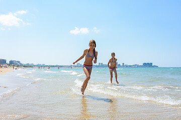 Image showing Two girlfriends run along the coastal strip of the sea coast
