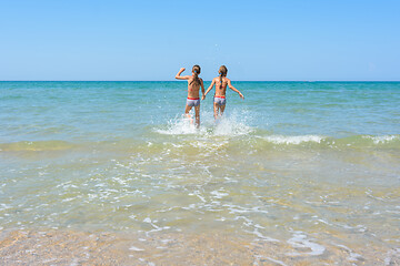 Image showing Girls run in the water swimming in shallow water