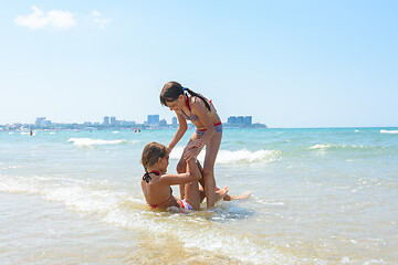 Image showing Two girls wallow each other in shallow sea