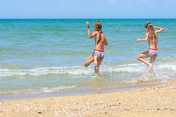 Image showing Two sisters run into the sea on a hot sunny day