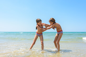 Image showing Two girls fight on the sandy beach of the sea