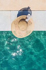 Image showing Woman wearing big summer sun hat relaxing on pier by clear turquoise sea.