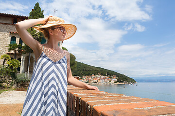 Image showing Lady wearing striped summer dress and straw hat relaxing on vaction enjoying view over beach at Moscenicka Draga, Istria, Croatia