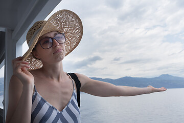 Image showing Disappointed female tourist on summer cruss ship vacation, checking if it rains, looking angry at overcast cloudy sky. Allways take the weather with you on summer vacations