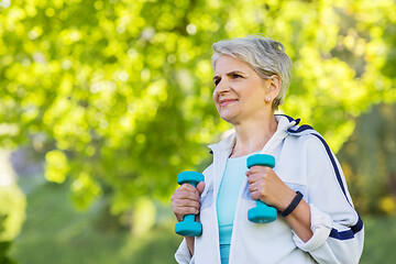 Image showing senior woman with dumbbells exercising at park