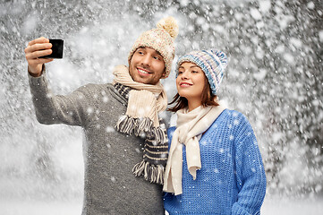 Image showing couple in winter hats taking selfie by smartphone