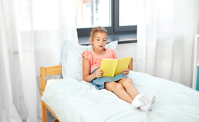 Image showing happy little girl reading book at home