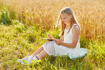 Image showing smiling girl writing to diary on cereal field