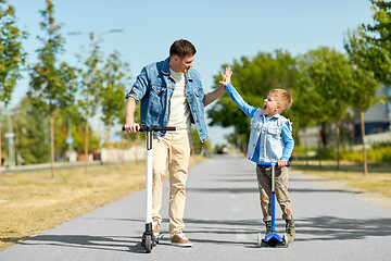 Image showing father and son with scooters making high five