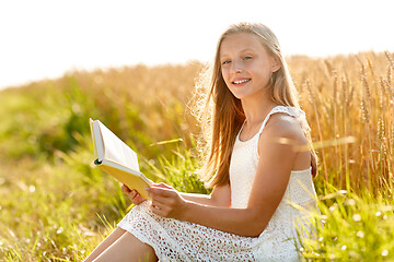 Image showing smiling young girl reading book on cereal field