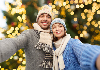 Image showing happy couple taking selfie over christmas lights