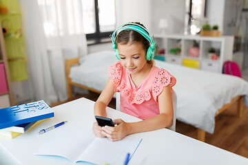 Image showing girl in headphones listening to music on cellphone