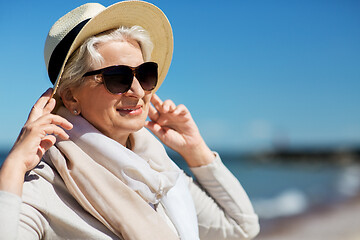 Image showing happy senior woman in sunglasses and hat on beach