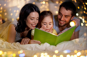 Image showing happy family reading book in bed at night at home