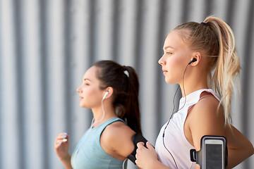 Image showing young women with earphones and smartphones running