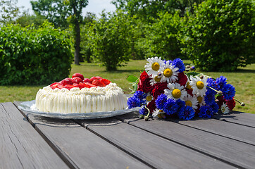 Image showing Green garden with cream cake and flowers