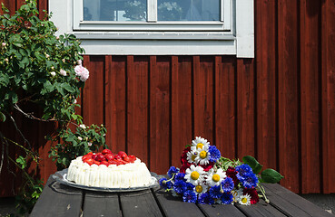 Image showing Decorated summer table in front of a red house