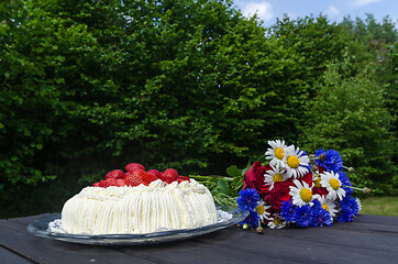 Image showing Cream cake and summer flowers in a garden