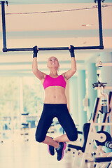 Image showing young woman in fitness gym lifting on bar