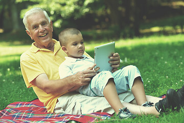 Image showing grandfather and child in park using tablet