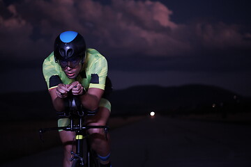 Image showing triathlon athlete riding bike fast at night