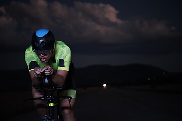 Image showing triathlon athlete riding bike fast at night