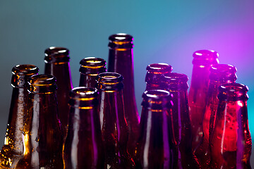 Image showing Neon colored beer bottles. Close up on bright studio background